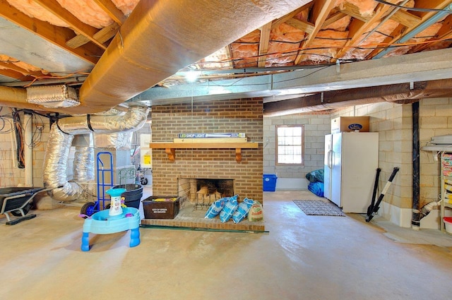 below grade area featuring freestanding refrigerator, a fireplace, and concrete block wall