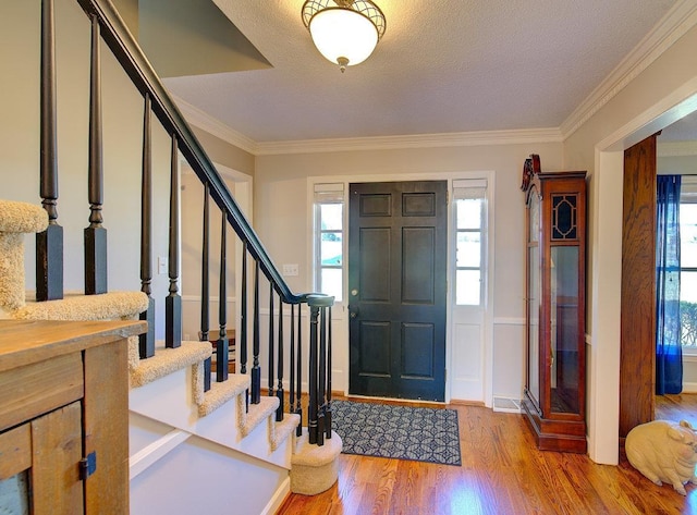 entryway with a healthy amount of sunlight, crown molding, a textured ceiling, and wood finished floors