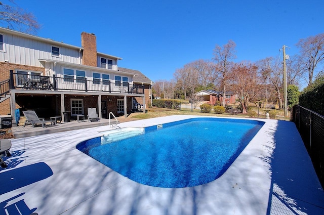view of swimming pool with a wooden deck, fence, a fenced in pool, and a patio