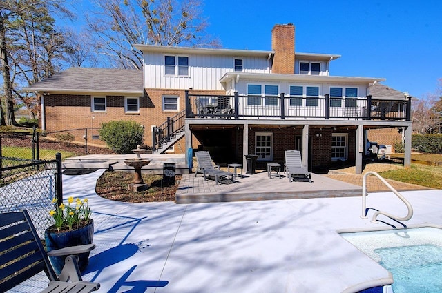 back of property with stairs, fence, a deck, a patio area, and brick siding