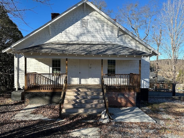 view of front of home featuring a porch, cooling unit, and a shingled roof