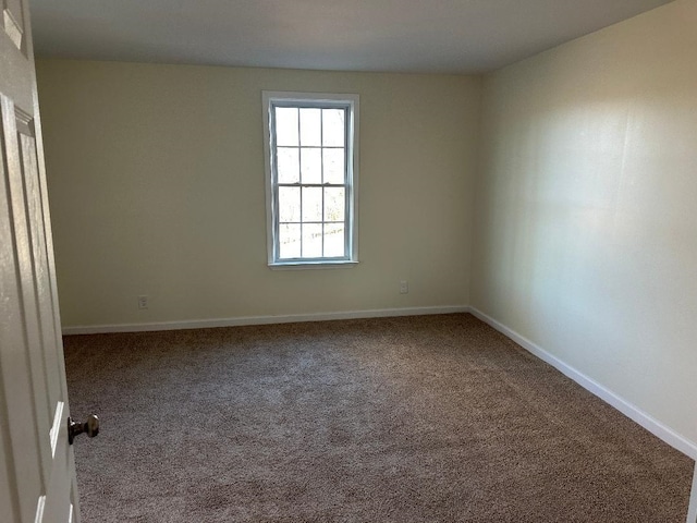 carpeted spare room featuring baseboards