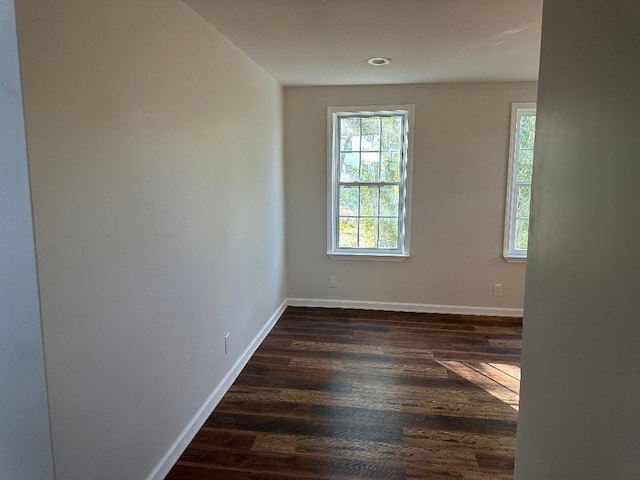 spare room featuring dark wood finished floors and baseboards