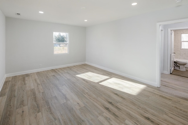 empty room with light wood-style floors, recessed lighting, visible vents, and baseboards