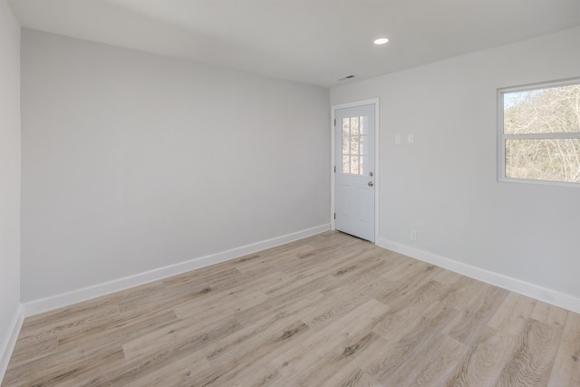 unfurnished room with light wood finished floors, plenty of natural light, baseboards, and recessed lighting