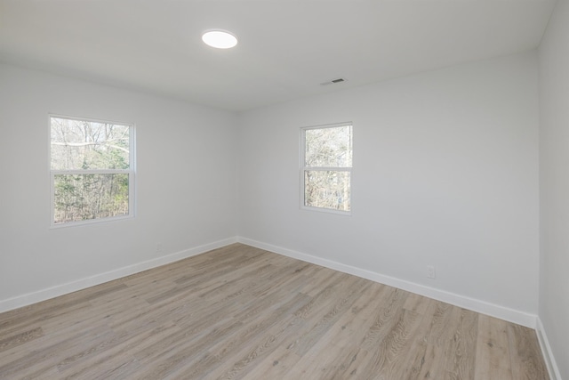 unfurnished room with light wood finished floors, visible vents, and baseboards