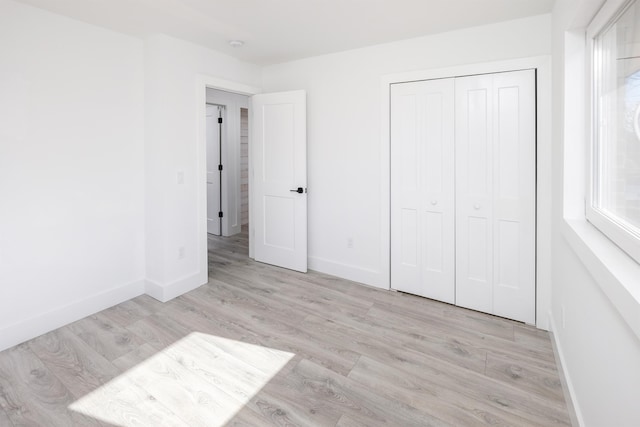 unfurnished bedroom featuring light wood-style floors, a closet, and baseboards