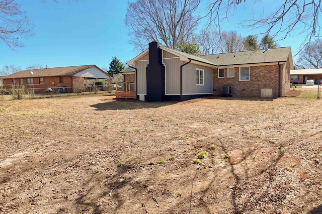 back of house featuring brick siding, fence, and a chimney