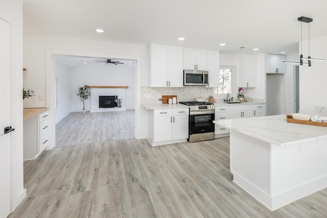 kitchen featuring appliances with stainless steel finishes, light wood-type flooring, white cabinets, and tasteful backsplash