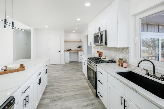 kitchen featuring open shelves, tasteful backsplash, appliances with stainless steel finishes, light wood-style floors, and a sink