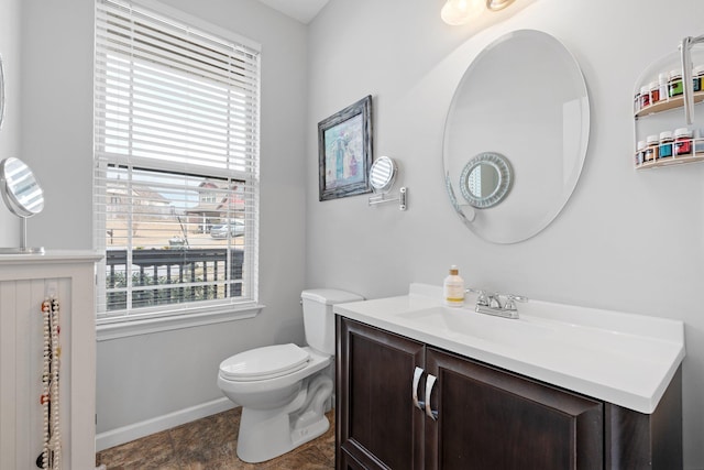 bathroom featuring toilet, baseboards, and vanity