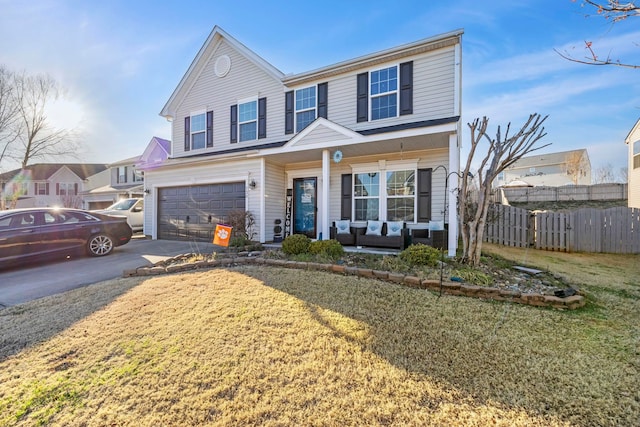 traditional-style house with a porch, concrete driveway, an attached garage, fence, and a front lawn