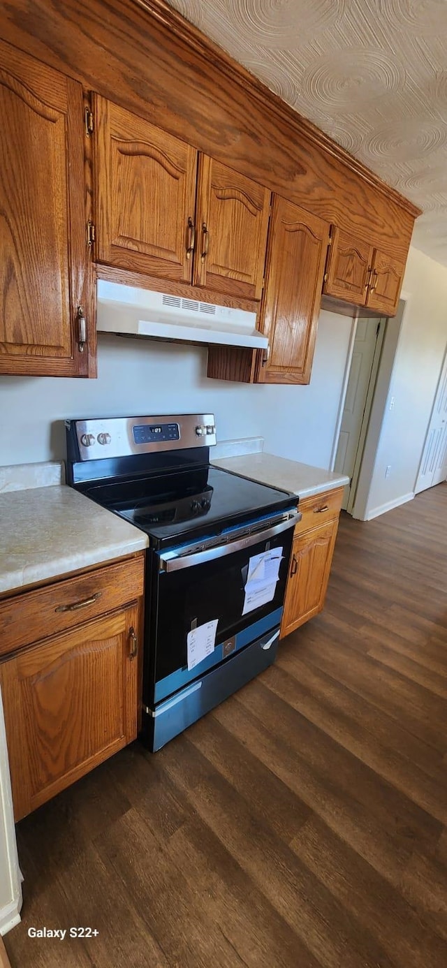 kitchen featuring dark wood-style floors, brown cabinets, light countertops, electric range, and under cabinet range hood