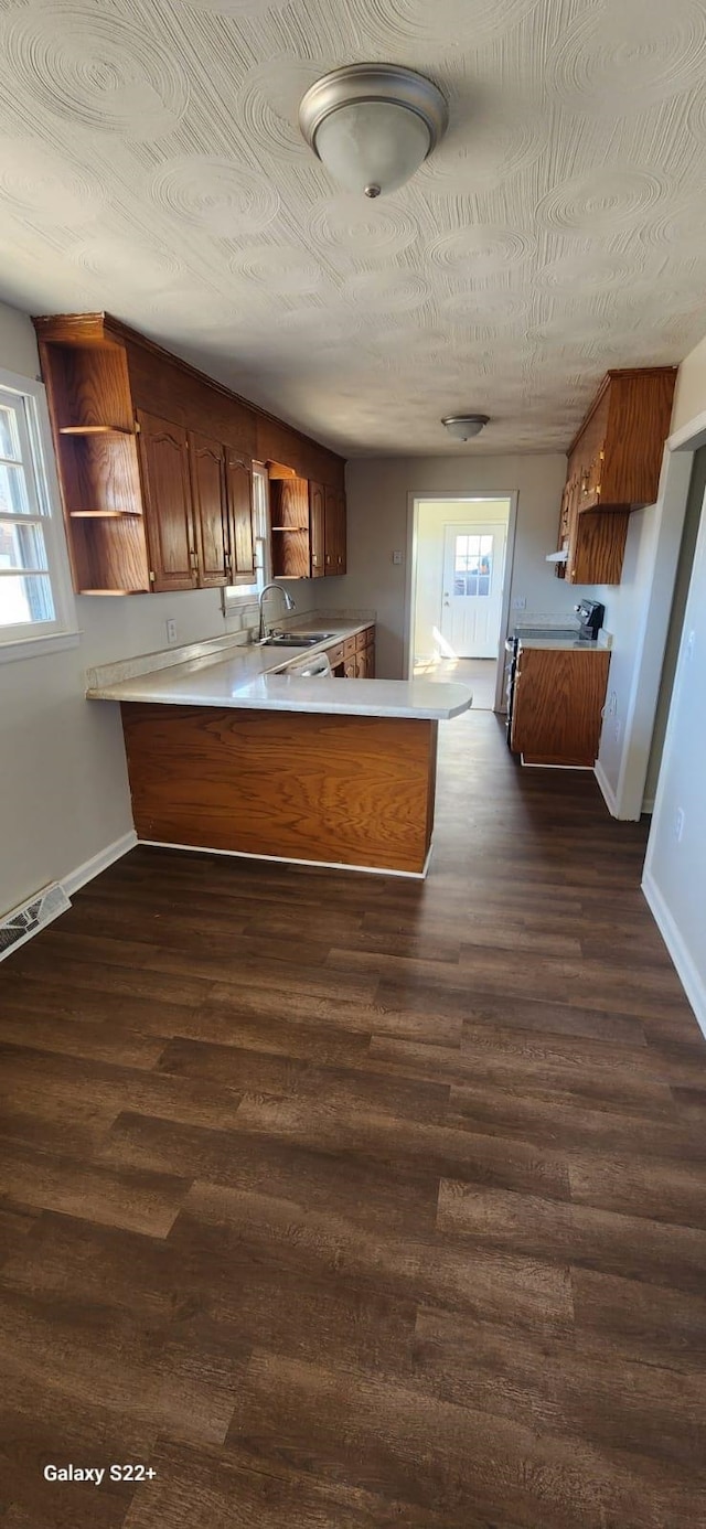 kitchen featuring dark wood-style floors, a sink, a peninsula, and open shelves