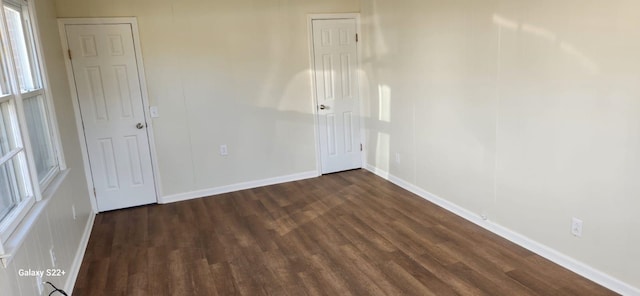 spare room featuring dark wood-style floors and baseboards