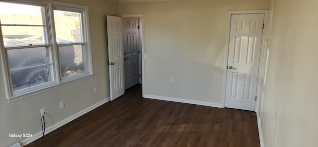 empty room featuring dark wood-style floors, visible vents, and baseboards