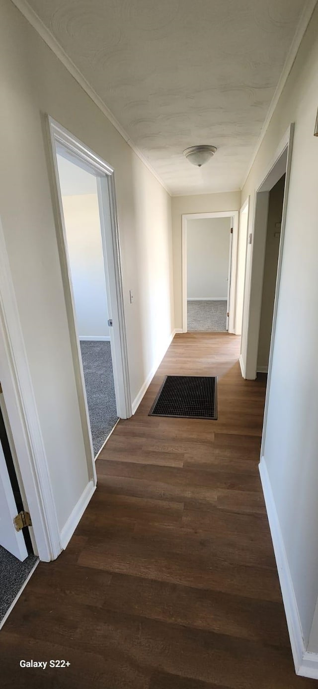 corridor with ornamental molding, baseboards, and wood finished floors