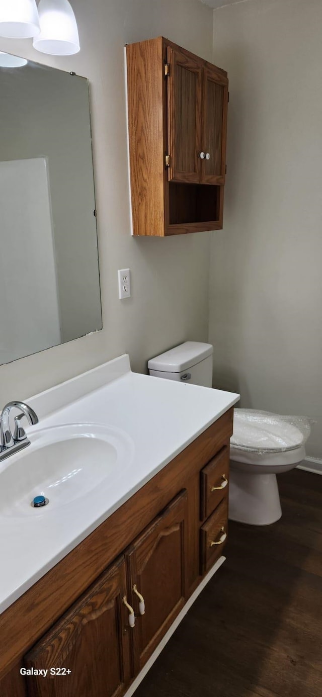 half bath with wood finished floors, vanity, and toilet