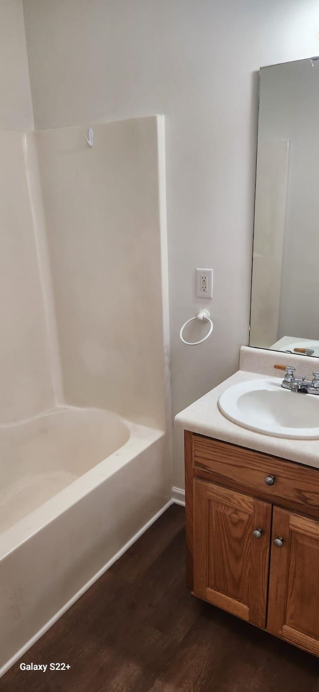 bathroom with a bathtub, wood finished floors, and vanity