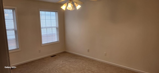 carpeted spare room with ceiling fan, visible vents, and baseboards