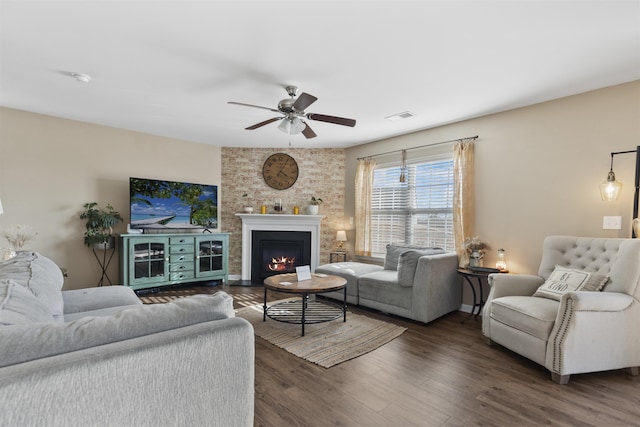 living area featuring visible vents, baseboards, a ceiling fan, a fireplace with flush hearth, and wood finished floors