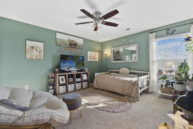 carpeted bedroom with a ceiling fan and visible vents