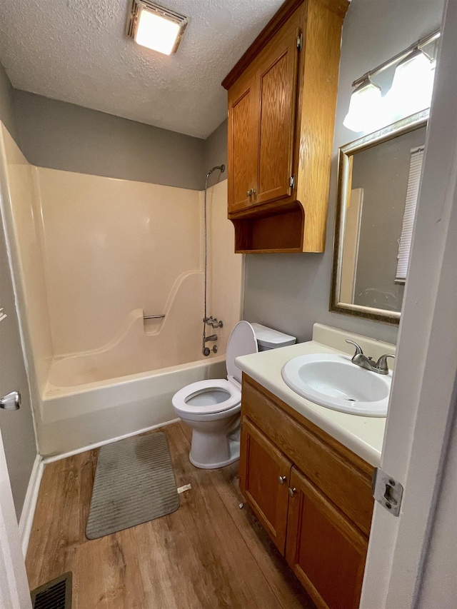 full bathroom featuring visible vents, toilet, wood finished floors, a textured ceiling, and vanity