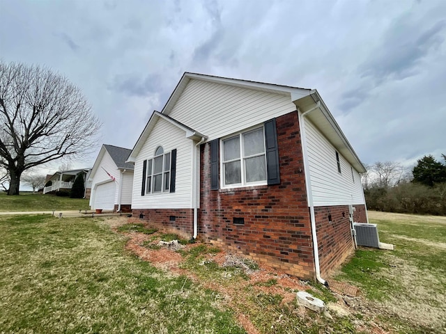 view of side of home featuring brick siding, central air condition unit, a lawn, an attached garage, and crawl space