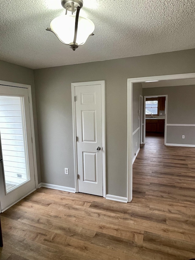 unfurnished room featuring a textured ceiling, baseboards, and wood finished floors