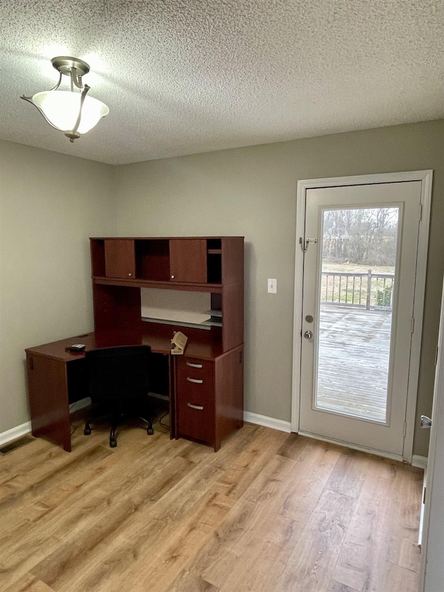 office area featuring light wood-style floors, a textured ceiling, and baseboards