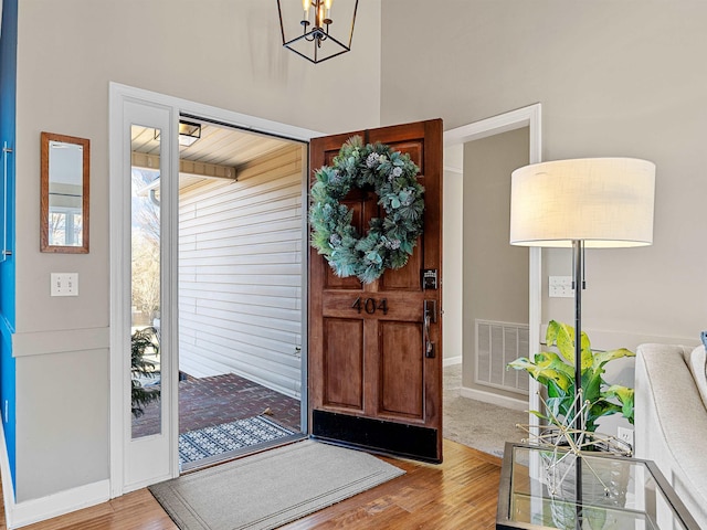 foyer featuring a notable chandelier, visible vents, and wood finished floors