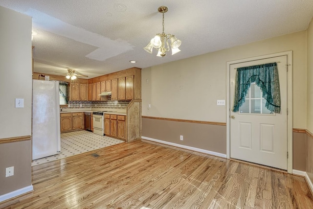 kitchen featuring brown cabinetry, white appliances, light countertops, and light wood finished floors