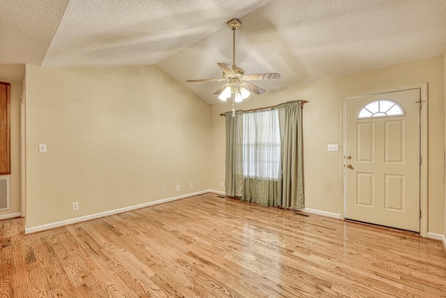 entryway with light wood finished floors, baseboards, a ceiling fan, lofted ceiling, and a textured ceiling