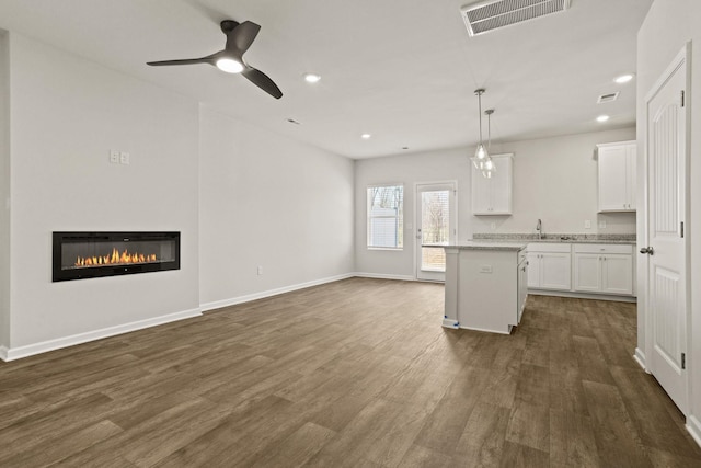 kitchen featuring visible vents, white cabinetry, dark wood-style flooring, and a sink