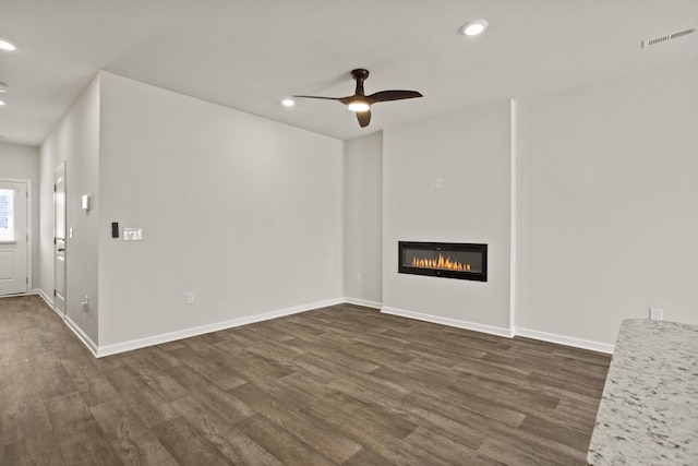 unfurnished living room with dark wood finished floors, a glass covered fireplace, and recessed lighting