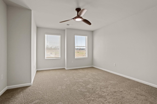 empty room featuring carpet floors, visible vents, ceiling fan, and baseboards