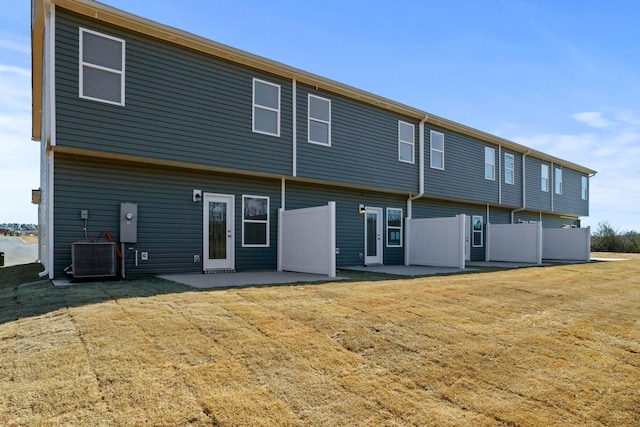 rear view of house with a patio, central AC unit, a lawn, and fence