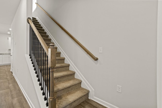 stairway with recessed lighting, wood finished floors, and baseboards