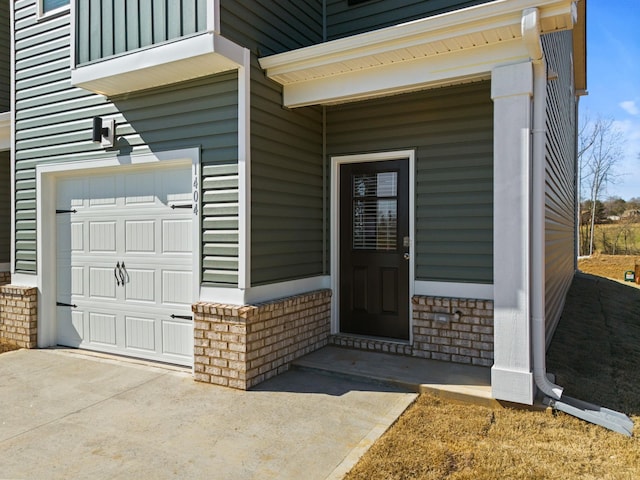 property entrance featuring driveway, brick siding, and an attached garage