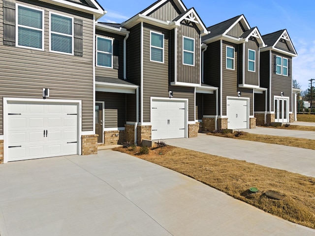 view of front of home with a garage, driveway, board and batten siding, and brick siding