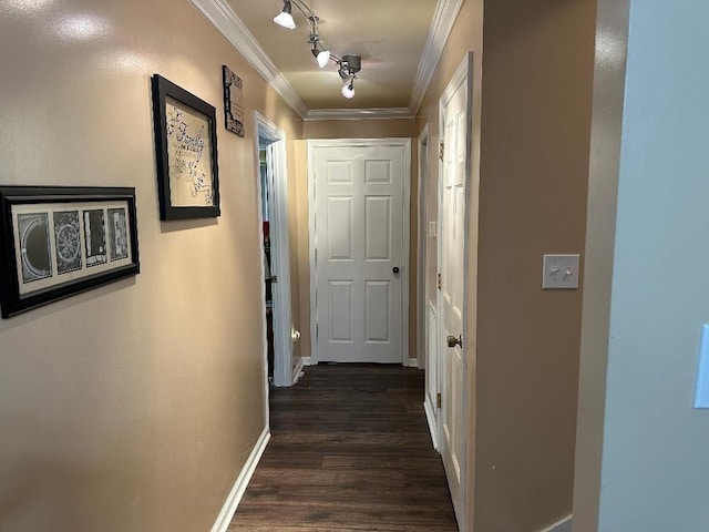 corridor with dark wood-style floors, baseboards, crown molding, and rail lighting