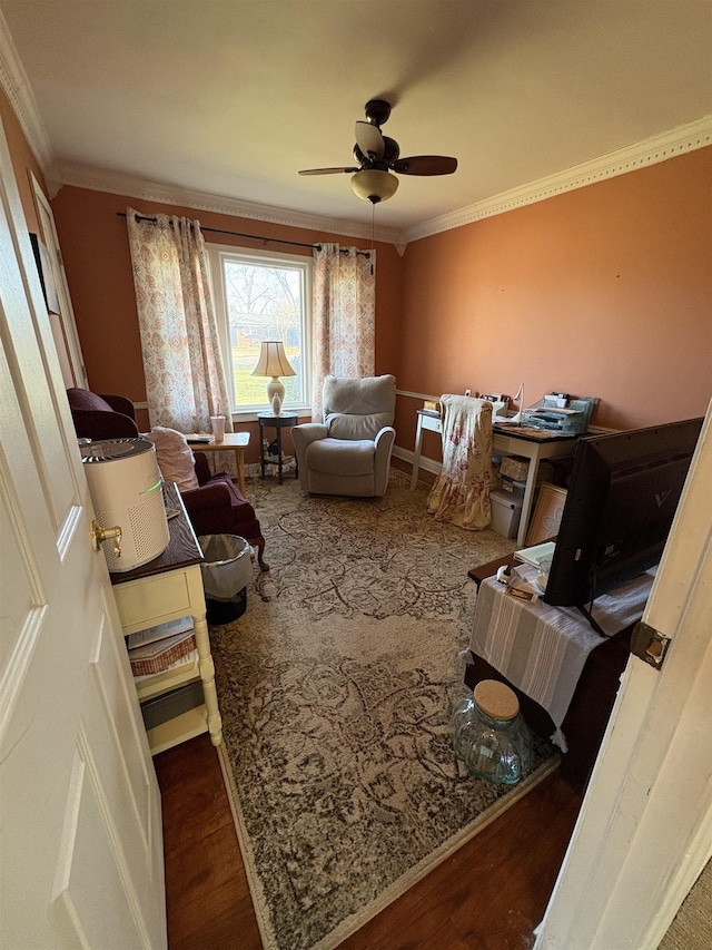 sitting room with a ceiling fan, crown molding, baseboards, and wood finished floors