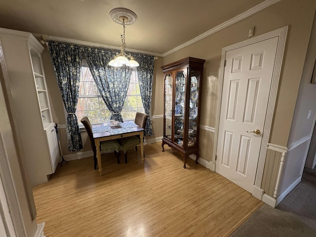 dining room with light wood finished floors, baseboards, and ornamental molding