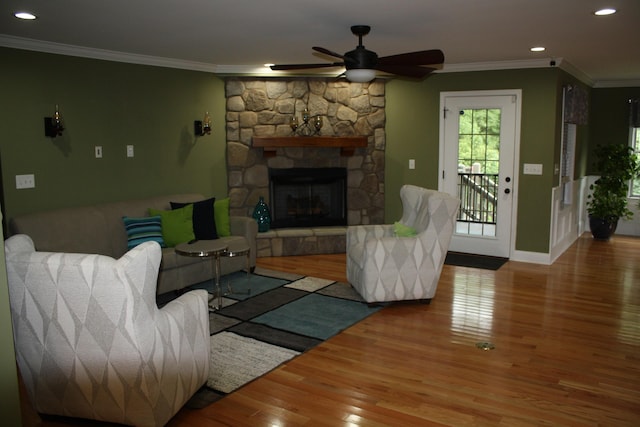 living area with baseboards, wood finished floors, crown molding, a fireplace, and recessed lighting