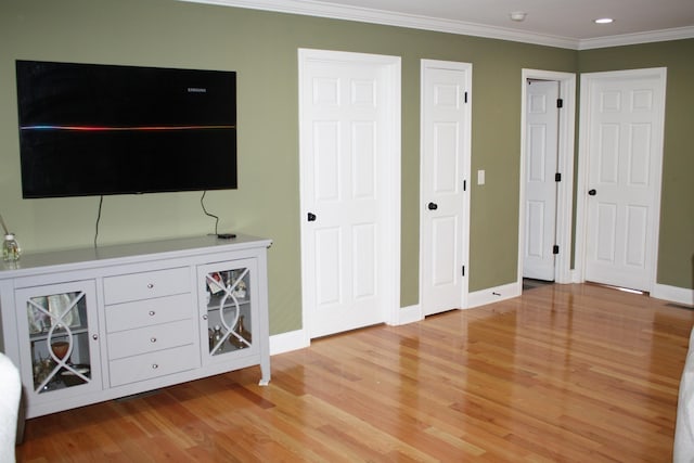 unfurnished bedroom with light wood finished floors, ornamental molding, and baseboards