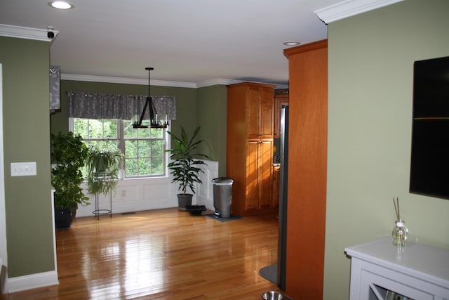 dining area with light wood-style floors, a chandelier, and crown molding