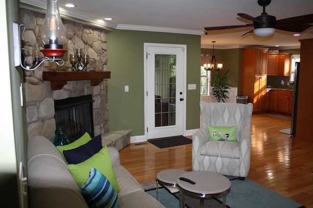 living room featuring light wood-style flooring, a fireplace, baseboards, and crown molding