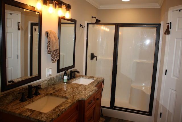 bathroom featuring crown molding, double vanity, a sink, and a shower stall