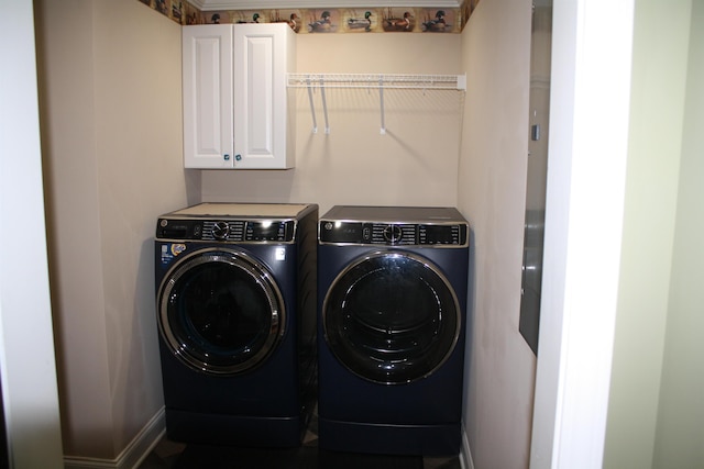 clothes washing area featuring separate washer and dryer, cabinet space, and baseboards