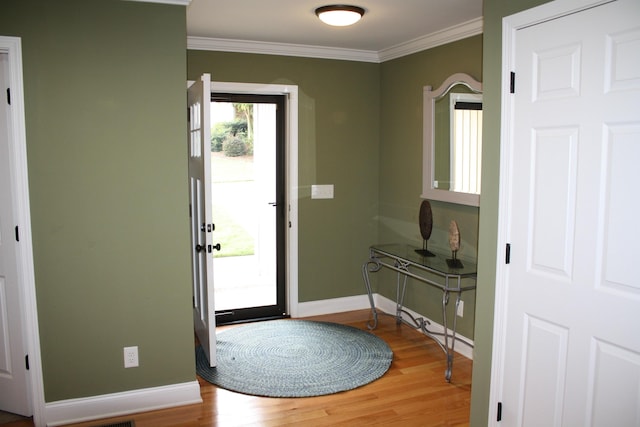 foyer featuring crown molding, baseboards, and wood finished floors